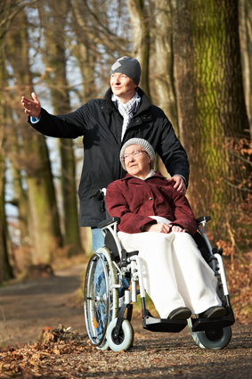 Elderly woman in wheelchair walking with son
